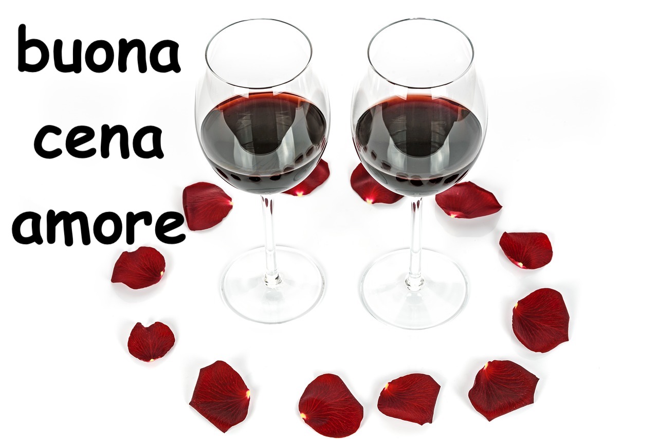  due calici di vino circondati da foglie di rose rosse 